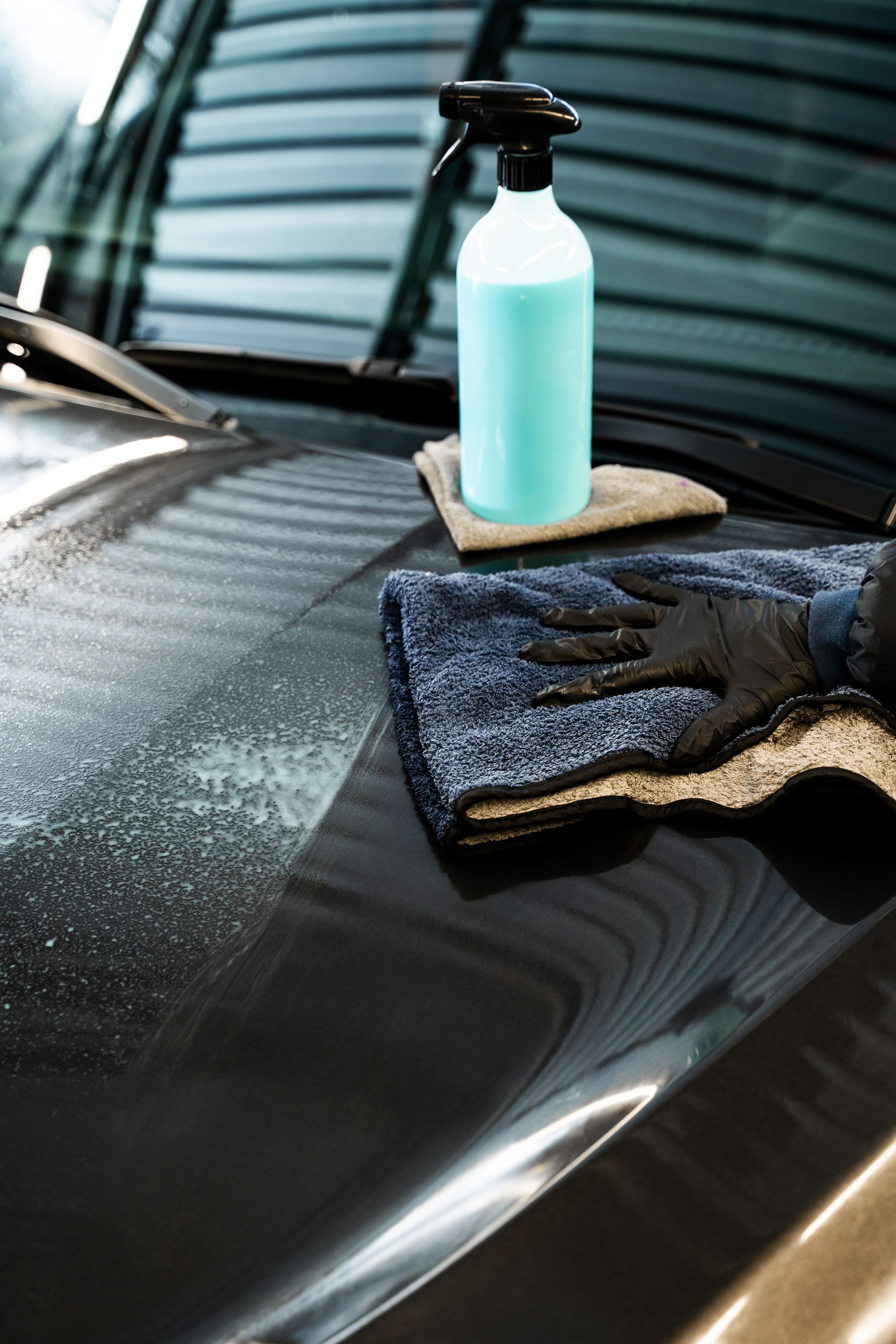 Applying quick detailer, spray and wiping to make clean and shine car surface. Polishing car body using microfiber cloth. Professional car valeting.