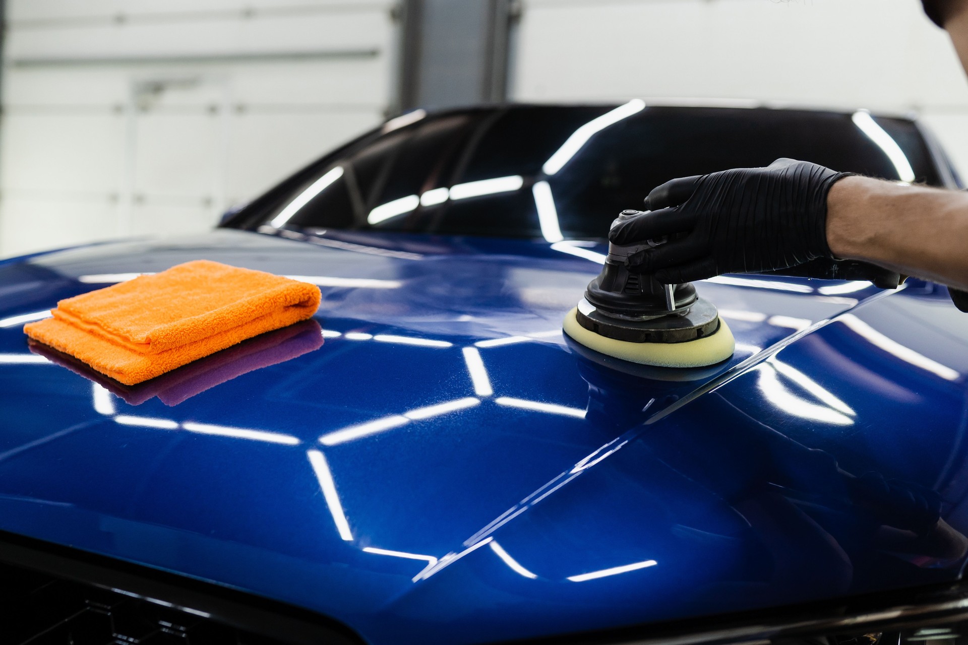 Sealant car polishing with orbital polisher for remove scratches. Worker of detailing auto service making final polishing for car.